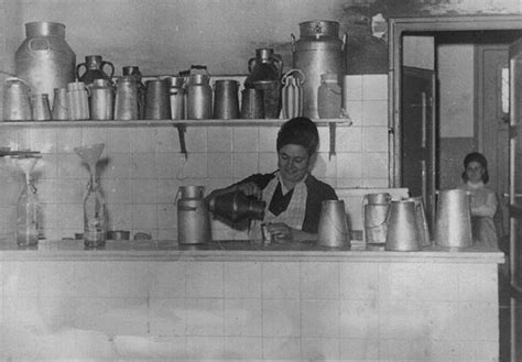 Foto histórica de una lechería antigua o un mercado rural con tinajas de leche