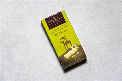 Fotografía: tableta de chocolate con leche de camella y un camello de fondo en un paisaje desértico
