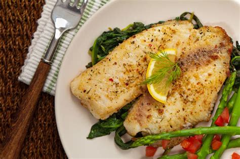 Plato de filete de pescado dorado con una generosa capa de cebolla caramelizada sobre una cama de patatas