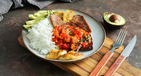 Plato de sobrebarriga en salsa criolla acompañado de arroz, yuca y aguacate