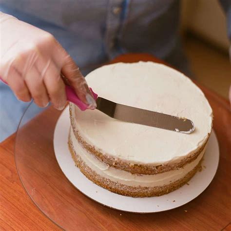 Ilustración de un pastel siendo alisado con espátula y scraper sobre un plato giratorio