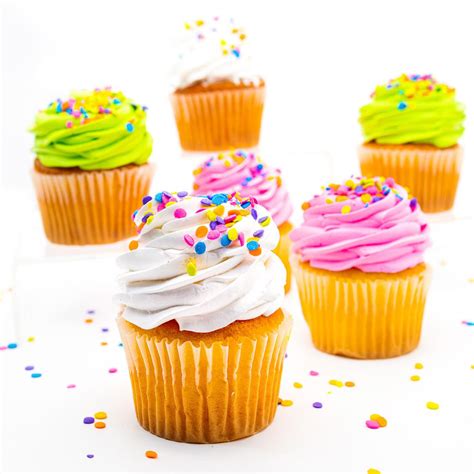 Foto de cupcakes de vainilla recién horneados, algunos con cobertura