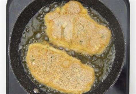 Cerdo rebozado dorado siendo escurrido después de la fritura.