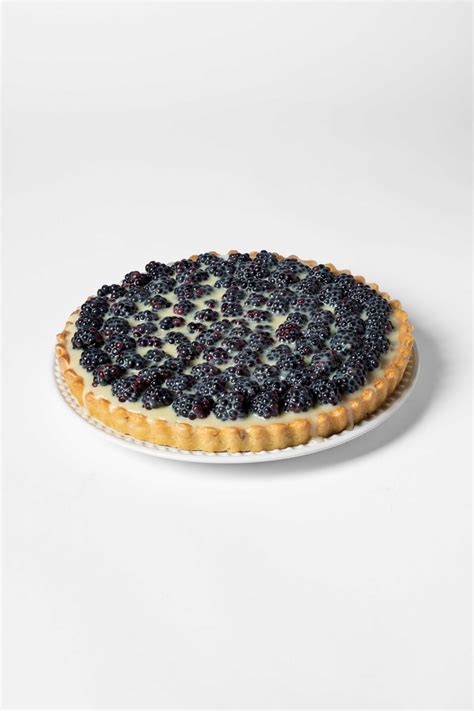 Fotografía de una tarta de zarzamora con una capa brillante de frutos rojos sobre una base crujiente