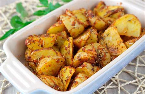 Fotografía de un plato de patatas horneadas espolvoreadas con especias frescas como romero y tomillo.