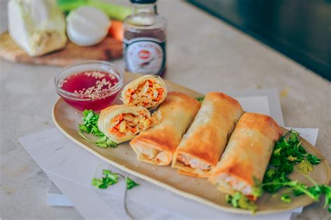 Fotografía profesional de un bol de salsa agridulce casera con rollitos primavera al lado