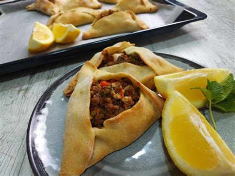 Empanadas árabes con carne en un plato, con limones a un lado