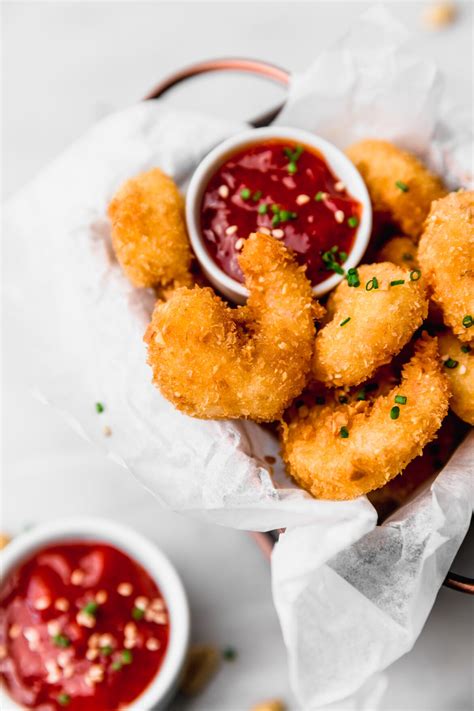 Plato de camarones empanizados al panko servidos con una salsa agridulce y rodajas de limón para decorar.