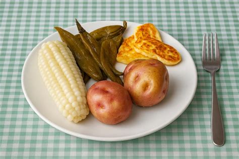 Fotografía gastronómica del plato paceño tradicional servido con sus ingredientes principales: choclo, habas, papa y queso dorado.