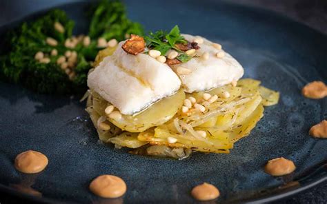Imagen de un plato de bacalao confitado con langostinos sobre chips de yuca