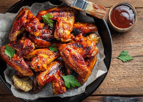 Fotografía de primer plano de alitas de pollo al horno con un glaseado brillante y aderezos frescos