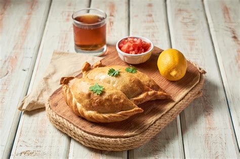 Variedad de empanadas latinoamericanas sobre una mesa con tazas de café y té