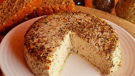Queso vegano de semillas de girasol cubierto de hierbas secas, con aros de olivas negras como decoración.