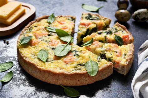 Ingredientes frescos para la tarta de salmón y espinacas, incluyendo salmón, espinacas, huevo y masa quebrada.