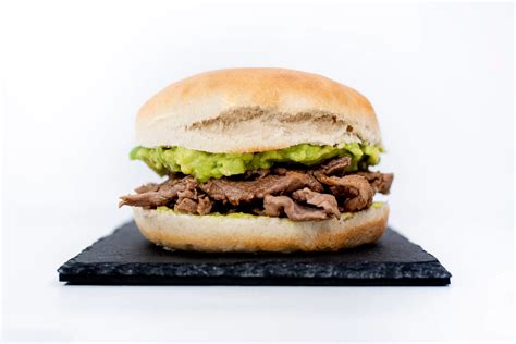 Churrasco chileno recién preparado con capas de carne, palta, tomate y mayonesa en pan batido