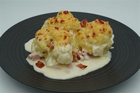 Molde con capas de puré de coliflor, jamón, queso y tomate, listo para hornear