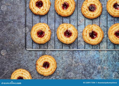 Galletas de mermelada recién horneadas en una bandeja, algunas con la mermelada visible en el centro.