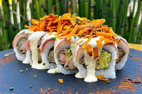 Ilustración de un roll estilo Nikkei con topping de camote frito y salsa acevichada.