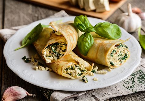 Plato elegante de panqueques rellenos con verduras frescas y decorados con brotes