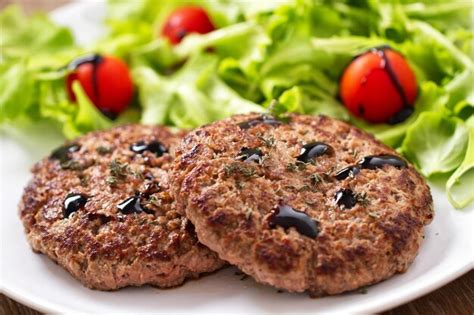 Foto de hamburguesas caseras de carne molida en un plato, con guarnición de patatas fritas y ensalada