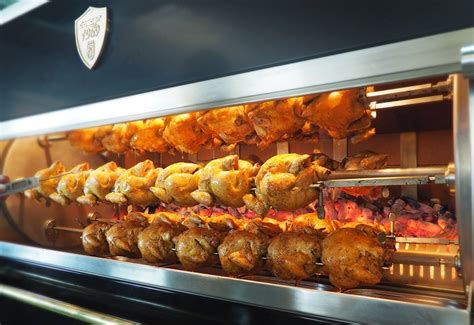 Foto de un mostrador de asador de pollos con pollos asados y acompañamientos