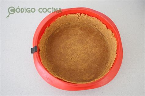 Proceso de preparación de la base de galletas para cheesecake, presionando con un vaso.