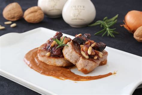 Plato de solomillo de cerdo sobre crema de patata y morcilla, decorado con frutos secos.