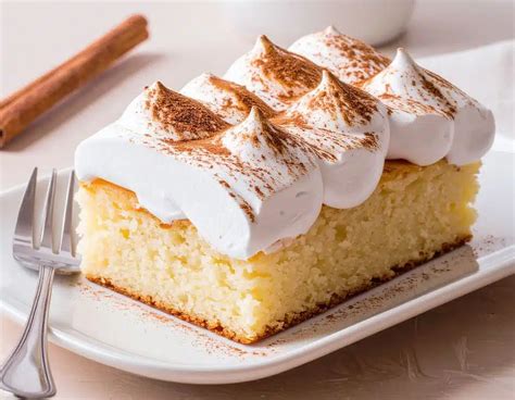 Imagen de un postre tres leches decorado con merengue dorado y frutas frescas.