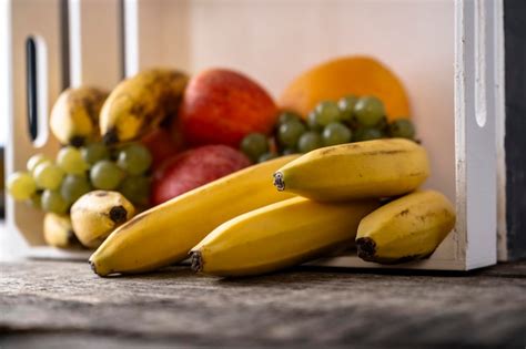 Plátanos maduros y manzanas frescas sobre una tabla de madera