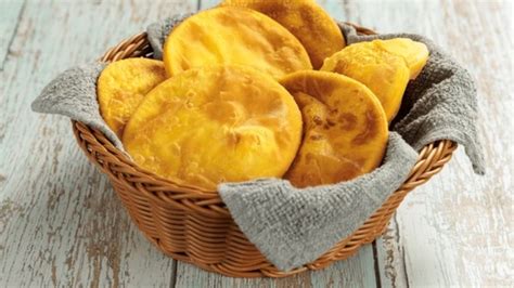 Fotografía de sopaipillas de levadura recién fritas y doradas, servidas en una fuente con papel absorbente.