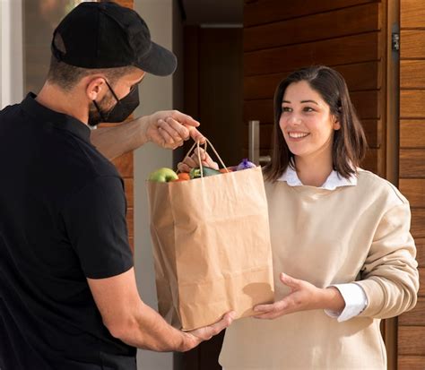 Una persona recibiendo una bolsa de supermercado en su puerta, entregada por un repartidor de Uber Eats