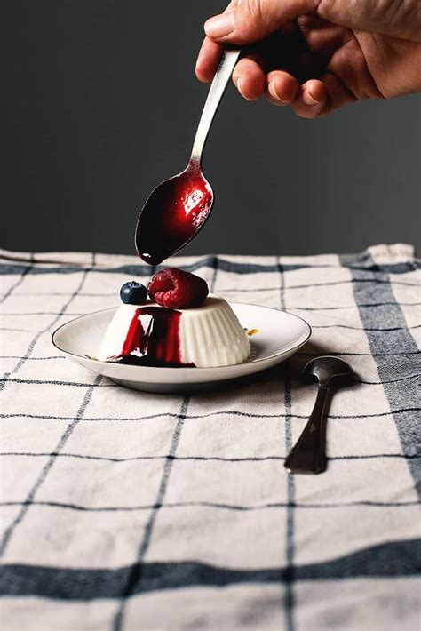 Fotografía de un coulis de frutos rojos brillante servido sobre una porción de tarta de queso