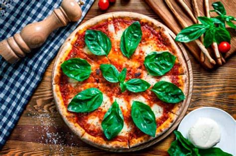 Fotografía gastronómica de una pizza artesanal con albahaca fresca y salami.