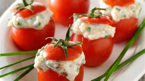 Foto de primeros planos de tomates cherry rellenos, decorados con ciboulette y servidos como aperitivo.