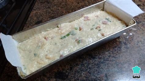 Disposición de ingredientes frescos para un budín salado, incluyendo pollo desmenuzado, verduras picadas, pan, huevos y queso