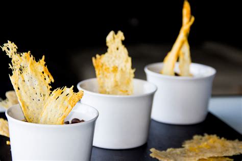 Plato de presentación con chips de queso parmesano dorados y crujientes sobre una mesa rústica.
