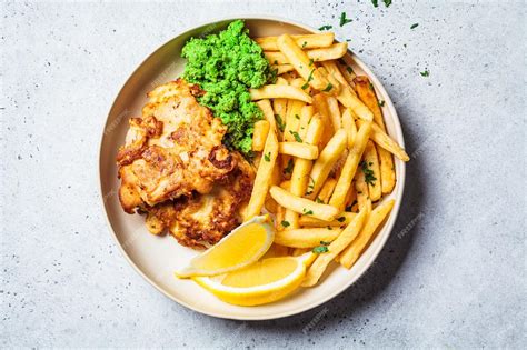 Emplatado de Fish and Chips con bacalao rebozado, patatas fritas y gajos de limón