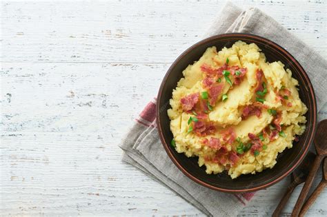 Un tazón de puré de papas cremoso con trocitos visibles de tocino y un toque de perejil picado.