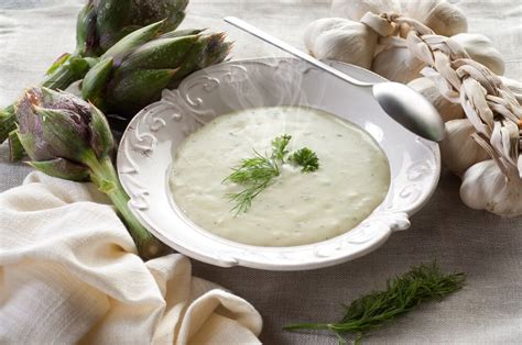 Fotografía de un bol con crema de alcachofa y parmesano decorada con virutas de queso y cebollino