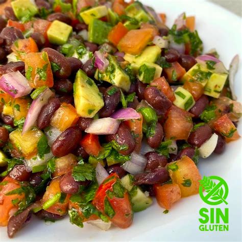 Plato de spaguetti de porotos negros con salsa de palta y decoración.