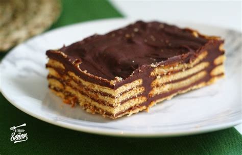 Fotografía de tarta de galletas terminada con una capa brillante de ganache de chocolate y frutos rojos decorativos.
