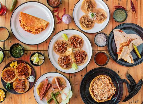 Fotografía de una mesa servida con varios platos chilenos caseros, incluyendo empanadas y guisos, en un ambiente rústico.