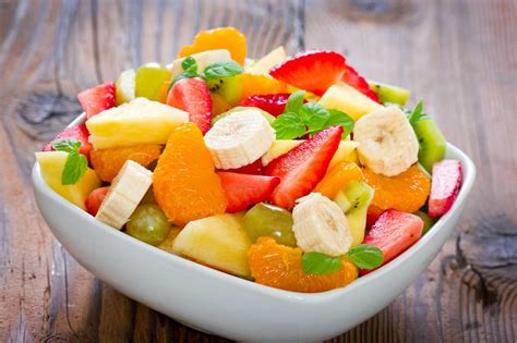 Macedonia de frutas frescas con texturas variadas servida en un bol de cristal.