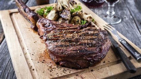 Fotografía de primer plano de un corte de carne Tomahawk servido en una tabla de madera