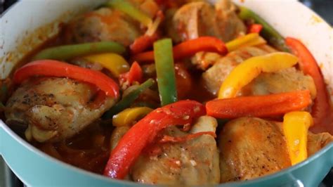 Plato de muslos de pollo cocinados con pimientos y cebolla, acompañado de arroz