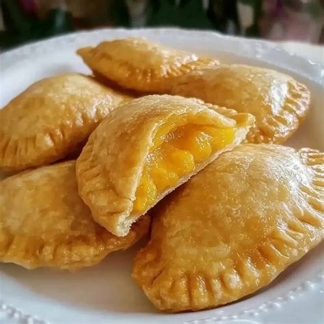 Plato de empanadas de piña recién horneadas con un té o café al fondo