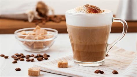 Foto de una taza de capuchino casero con canela y un frasco de mezcla en polvo