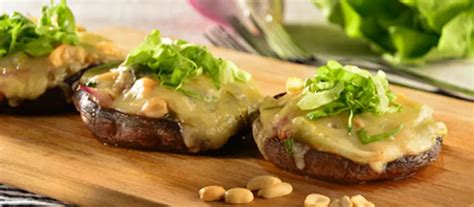 Fotografía profesional de champiñones jumbo rellenos servidos en un plato elegante con guarnición fresca.