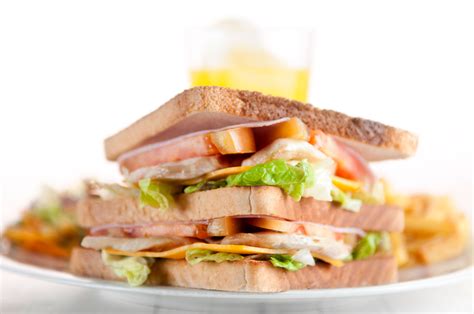 Fotografía gastronómica de un sándwich de lengua de vacuno servido en pan amasado con sus acompañamientos frescos.