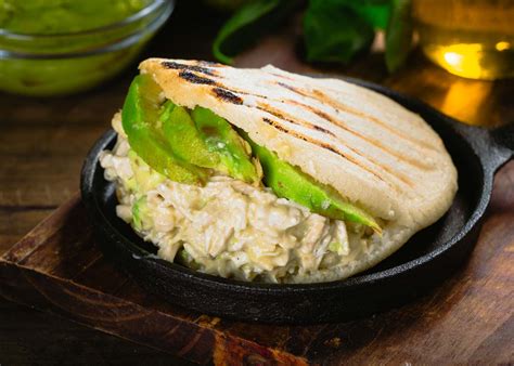 Foto detallada de una arepa venezolana tradicional abierta y rellena con la icónica Reina Pepiada.